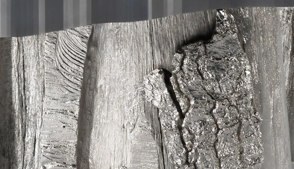 Placage de bois de marronnier, sur fond d’inox ti-black brossé.