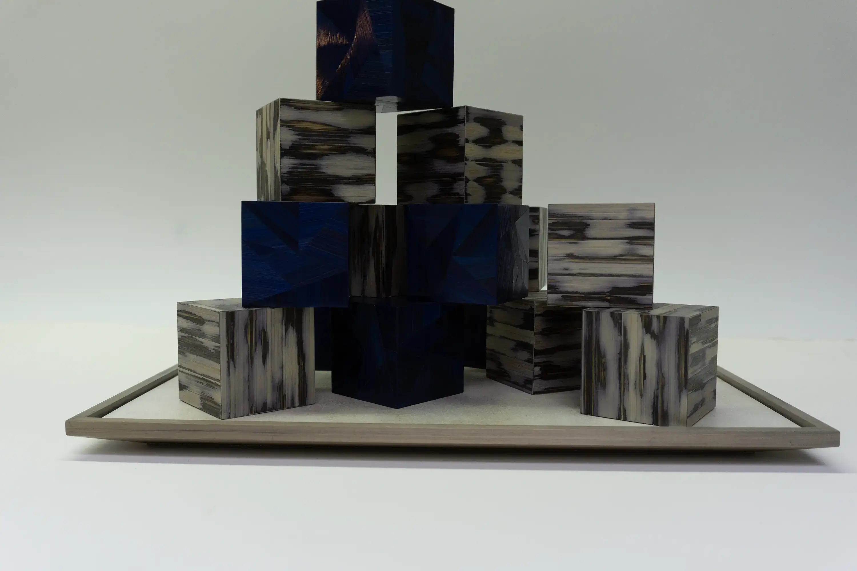 Réalisation d’un jeu de cubes pour l’exposition itinérante de la Maison Française. Cubes en marqueterie de paille bleue, motifs facettes. Cubes en marqueterie de paille, technique Maonia.