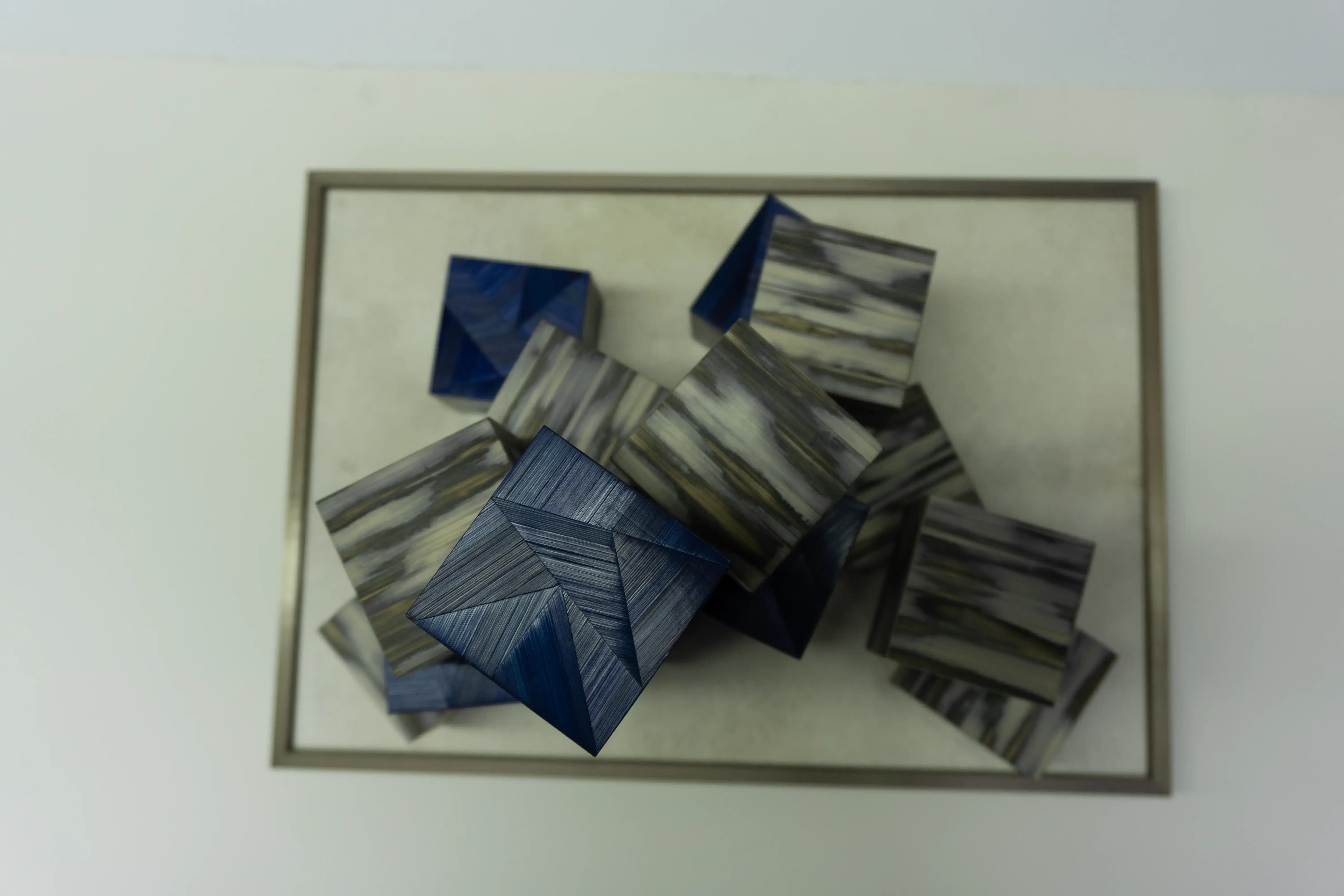 Réalisation d’un jeu de cubes pour l’exposition itinérante de la Maison Française. Cubes en marqueterie de paille bleue, motifs facettes. Cubes en marqueterie de paille, technique Maonia.